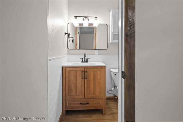 bathroom with hardwood / wood-style flooring, vanity, and toilet