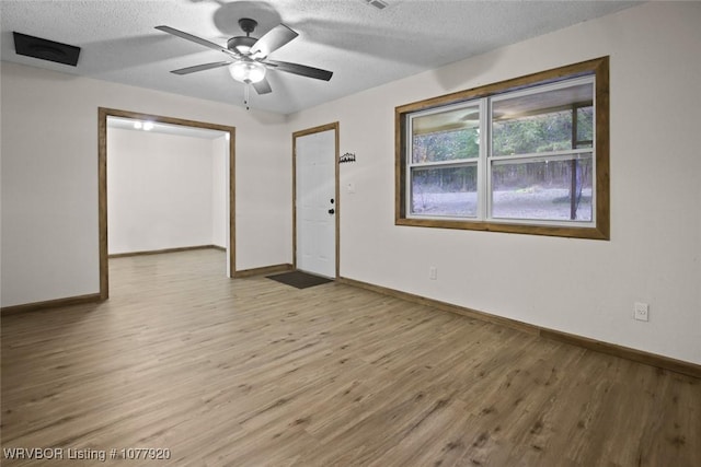 unfurnished room featuring a textured ceiling, light wood-type flooring, and ceiling fan