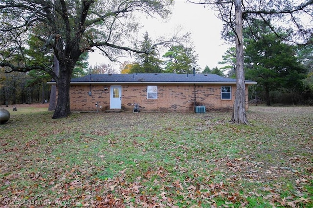 rear view of house with central AC unit and a yard