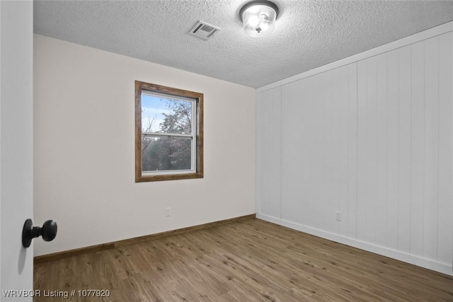 empty room with a textured ceiling and hardwood / wood-style flooring