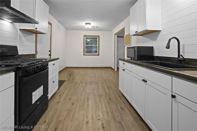 kitchen featuring white cabinets, sink, wall chimney exhaust hood, and black appliances