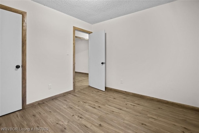 unfurnished bedroom featuring light hardwood / wood-style floors, a textured ceiling, and a closet