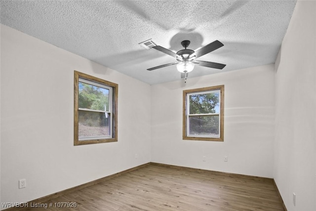 spare room featuring a wealth of natural light, light hardwood / wood-style flooring, ceiling fan, and a textured ceiling