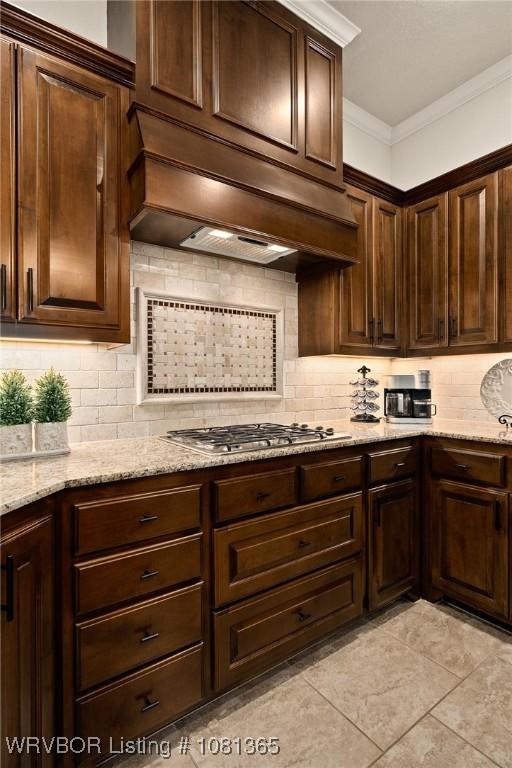 8404 Gatehouse Way, Fort Smith, AR 72916 - kitchen featuring stainless steel gas cooktop, ornamental molding, decorative backsplash, dark brown cabinets, and light stone counters