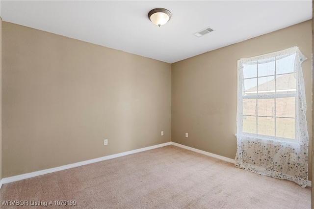 unfurnished room with carpet, a healthy amount of sunlight, visible vents, and baseboards