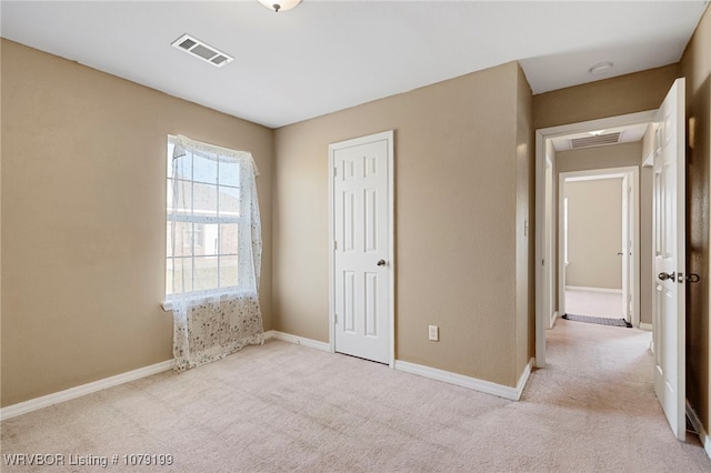 unfurnished bedroom featuring visible vents, light carpet, and baseboards