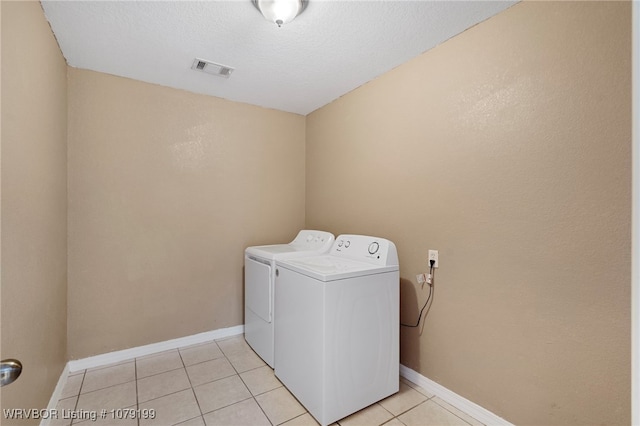 clothes washing area featuring light tile patterned floors, laundry area, visible vents, baseboards, and washer and clothes dryer