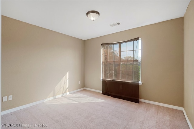 empty room with baseboards, visible vents, and light colored carpet