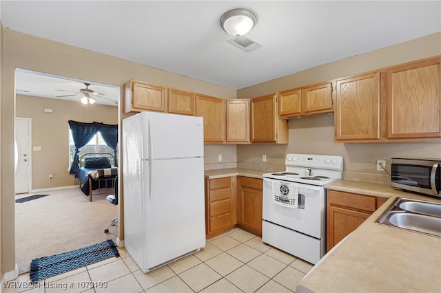 kitchen with light tile patterned floors, white appliances, a sink, visible vents, and light countertops