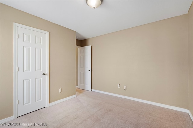 unfurnished bedroom with light colored carpet and baseboards