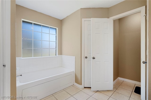 full bathroom with a garden tub, baseboards, and tile patterned floors