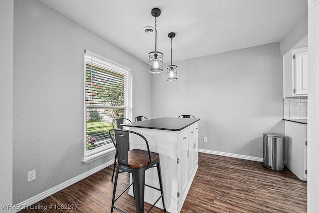 2509 Roxbury Ln, Fort Smith, AR 72908 - kitchen featuring dark countertops, white cabinets, dark wood-style flooring, hanging light fixtures, and a breakfast bar area