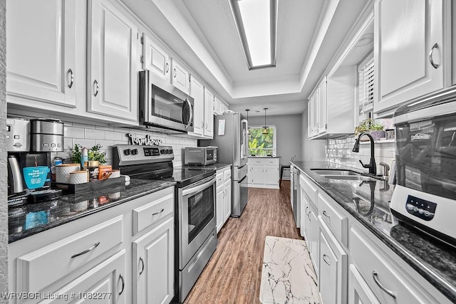 2509 Roxbury Ln, Fort Smith, AR 72908 - kitchen with appliances with stainless steel finishes, white cabinetry, wood finished floors, decorative backsplash, and dark stone countertops
