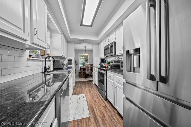 2509 Roxbury Ln, Fort Smith, AR 72908 - kitchen featuring appliances with stainless steel finishes, white cabinets, dark wood-style flooring, tasteful backsplash, and dark stone counters