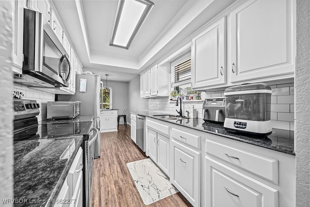 2509 Roxbury Ln, Fort Smith, AR 72908 - kitchen with appliances with stainless steel finishes, wood finished floors, white cabinetry, and backsplash