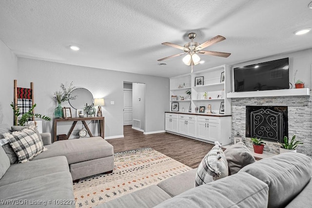 2509 Roxbury Ln, Fort Smith, AR 72908 - living room with a ceiling fan, dark wood-type flooring, a textured ceiling, a stone fireplace, and recessed lighting