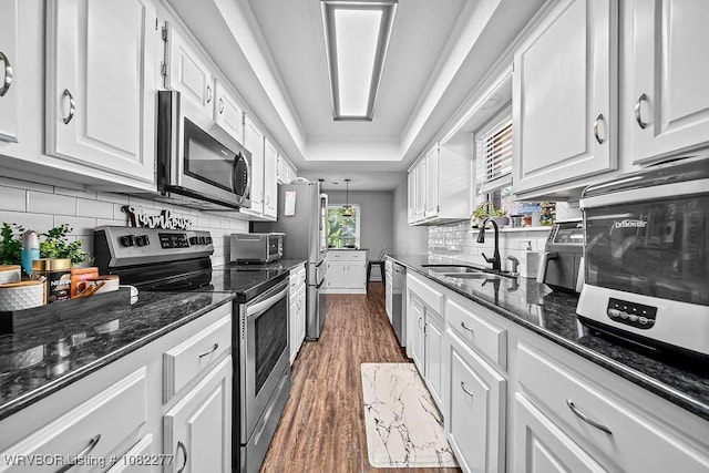 2509 Roxbury Ln, Fort Smith, AR 72908 - kitchen with appliances with stainless steel finishes, white cabinetry, dark wood-type flooring, tasteful backsplash, and dark stone countertops