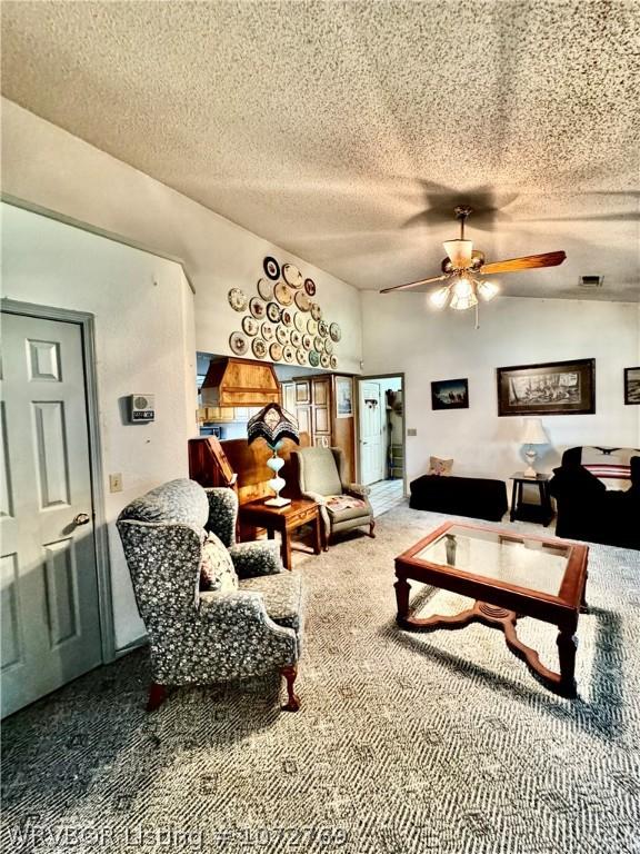 living room featuring carpet, ceiling fan, and a textured ceiling