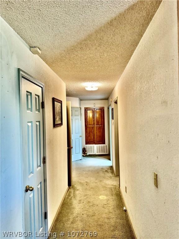 hallway featuring light carpet and a textured ceiling