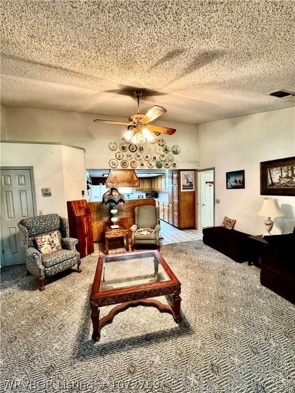 carpeted living room with ceiling fan and a textured ceiling