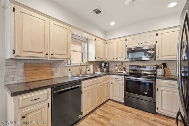 kitchen with visible vents, dark countertops, stainless steel appliances, light wood-style floors, and a sink