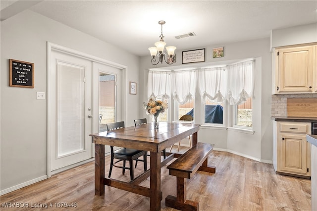 dining space featuring a chandelier, light wood-style flooring, visible vents, and baseboards