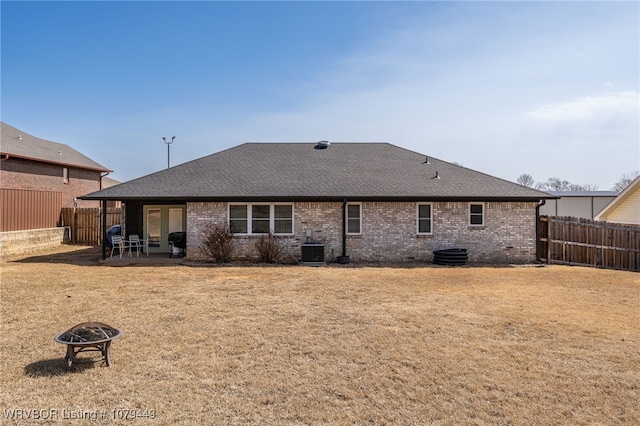 rear view of property featuring cooling unit, a patio area, brick siding, and a fire pit