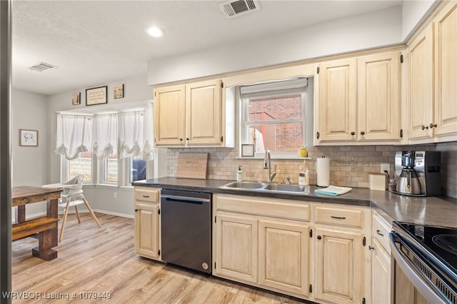 kitchen featuring dishwasher, dark countertops, a sink, and visible vents