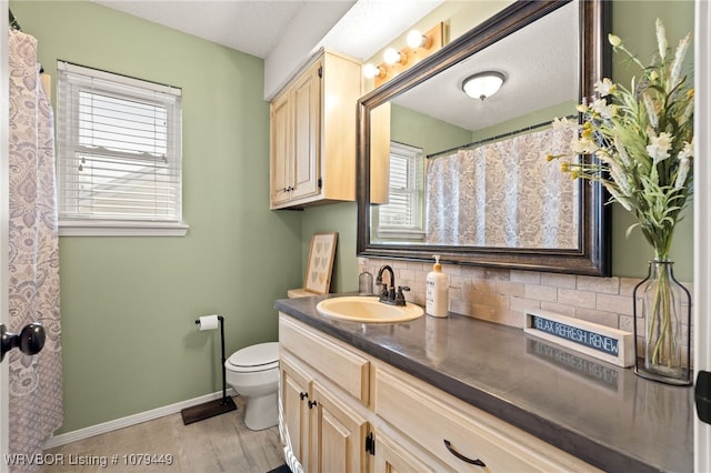 full bath with toilet, decorative backsplash, vanity, wood finished floors, and baseboards