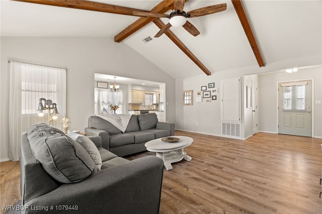 living room with plenty of natural light, visible vents, beamed ceiling, and light wood-style flooring