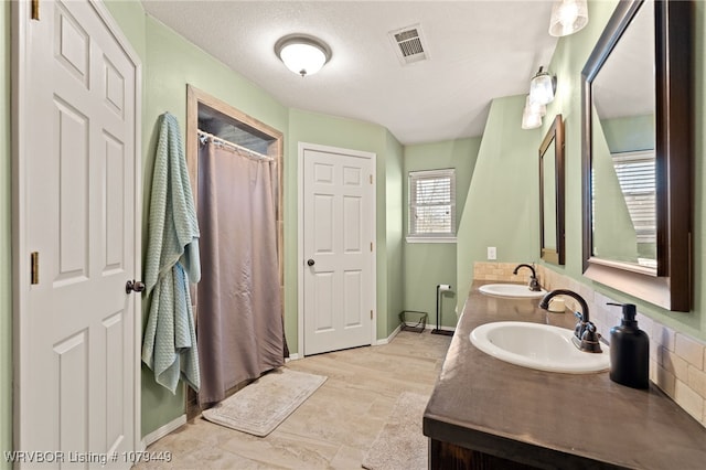 full bath featuring visible vents, a sink, baseboards, and double vanity