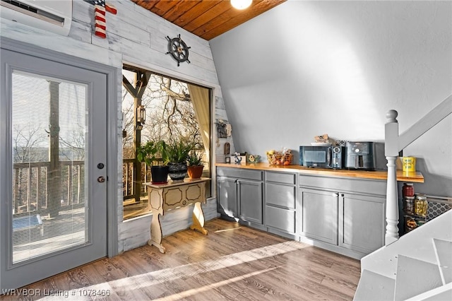 doorway to outside with wooden walls, wood ceiling, and light wood-type flooring