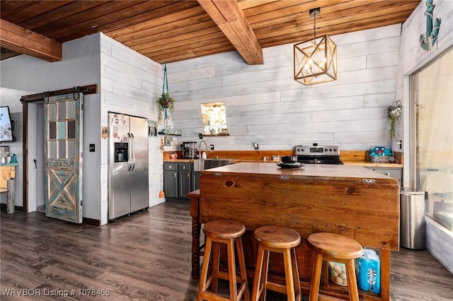 kitchen featuring appliances with stainless steel finishes, beamed ceiling, wood walls, wooden ceiling, and a barn door