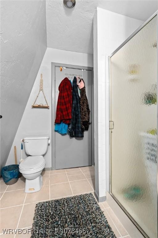 bathroom with vaulted ceiling, toilet, tile patterned floors, and an enclosed shower