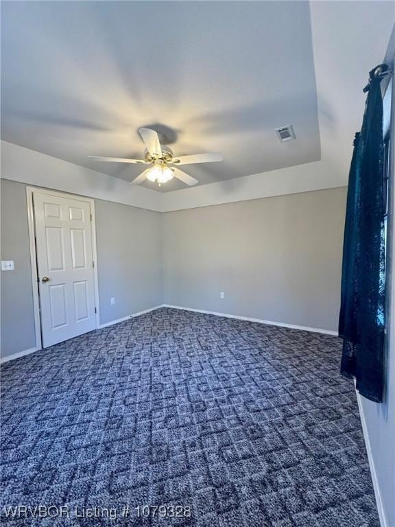 empty room with ceiling fan, carpet floors, visible vents, and baseboards