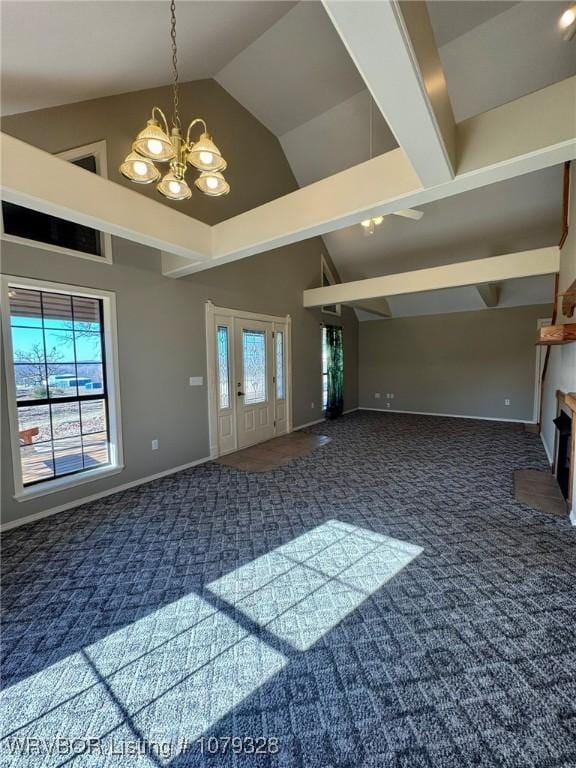 carpeted entrance foyer featuring high vaulted ceiling, a healthy amount of sunlight, baseboards, and an inviting chandelier