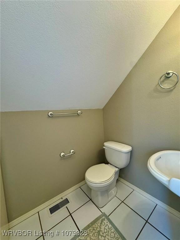 bathroom featuring toilet, visible vents, a textured ceiling, and tile patterned floors