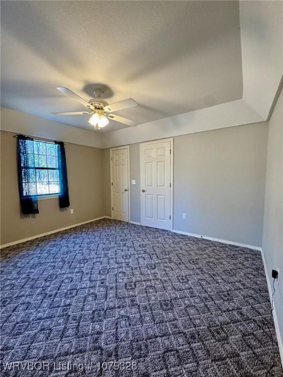 unfurnished bedroom with carpet floors, ceiling fan, baseboards, and a textured ceiling