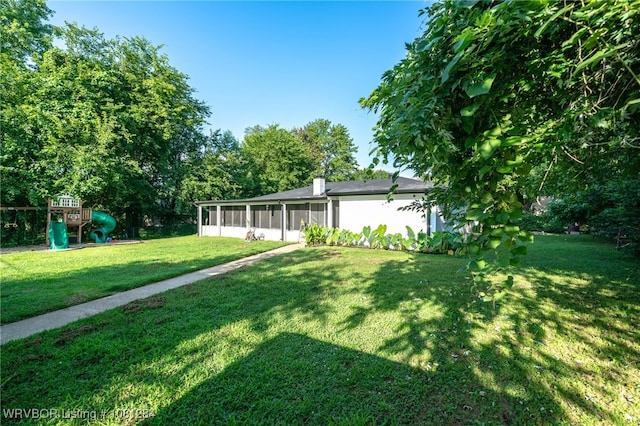 908 N 5th Ter, Barling, AR 72923 - view of front of property with a sunroom, a playground, a front lawn, and a chimney