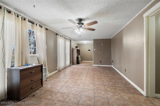 tiled spare room with wood walls, ceiling fan, a textured ceiling, and ornamental molding