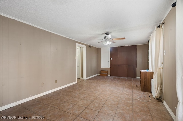 unfurnished room with a textured ceiling, wooden walls, ceiling fan, and crown molding