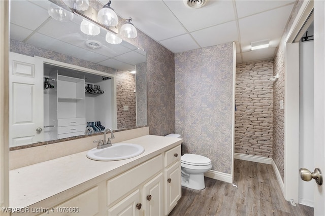 bathroom with a drop ceiling, vanity, wood-type flooring, and toilet