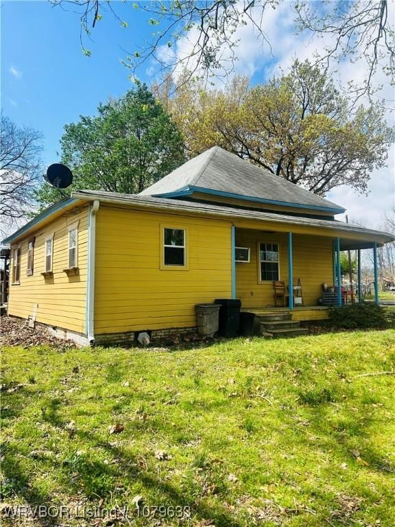 rear view of property featuring covered porch and a yard