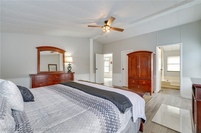 bedroom with ceiling fan, vaulted ceiling, ensuite bathroom, and light hardwood / wood-style flooring