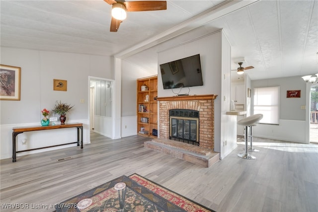 living room with ceiling fan, light hardwood / wood-style floors, and a fireplace