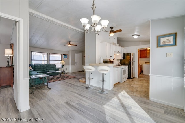 kitchen with lofted ceiling with beams, decorative light fixtures, light hardwood / wood-style flooring, white cabinetry, and a breakfast bar area