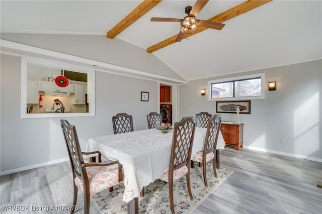 dining space featuring vaulted ceiling with beams, light hardwood / wood-style floors, washer / dryer, and ceiling fan