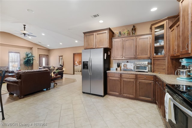 kitchen with vaulted ceiling, ceiling fan, light stone countertops, appliances with stainless steel finishes, and tasteful backsplash