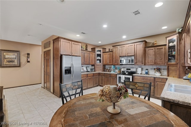 kitchen with sink, light stone countertops, stainless steel appliances, and tasteful backsplash