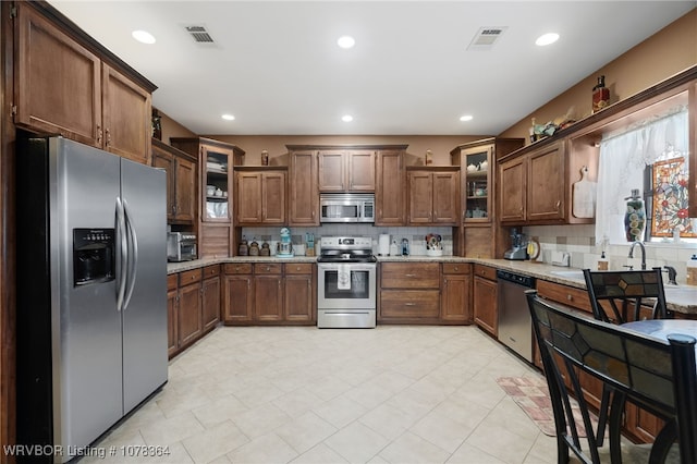 kitchen with backsplash, light stone counters, and appliances with stainless steel finishes